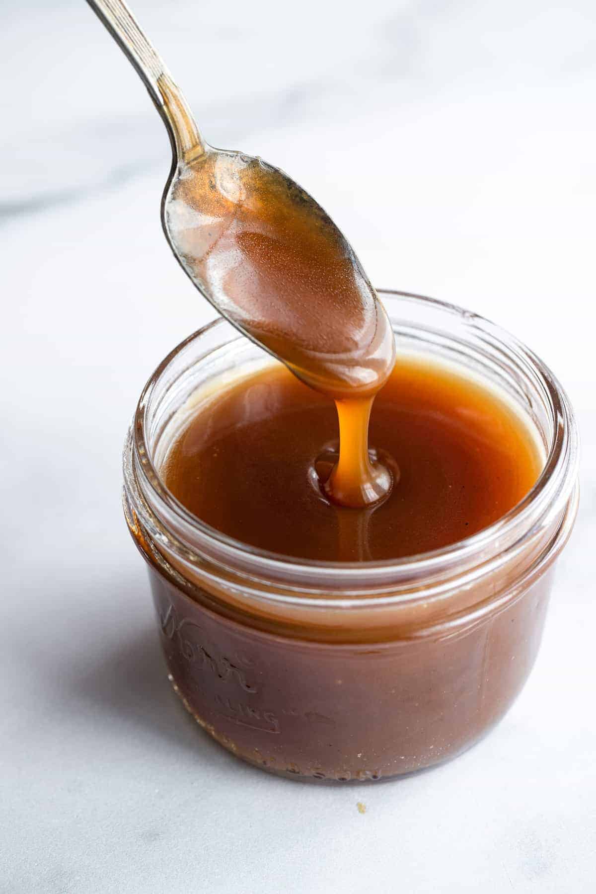 a spoon dipped in dairy free vegan caramel sauce