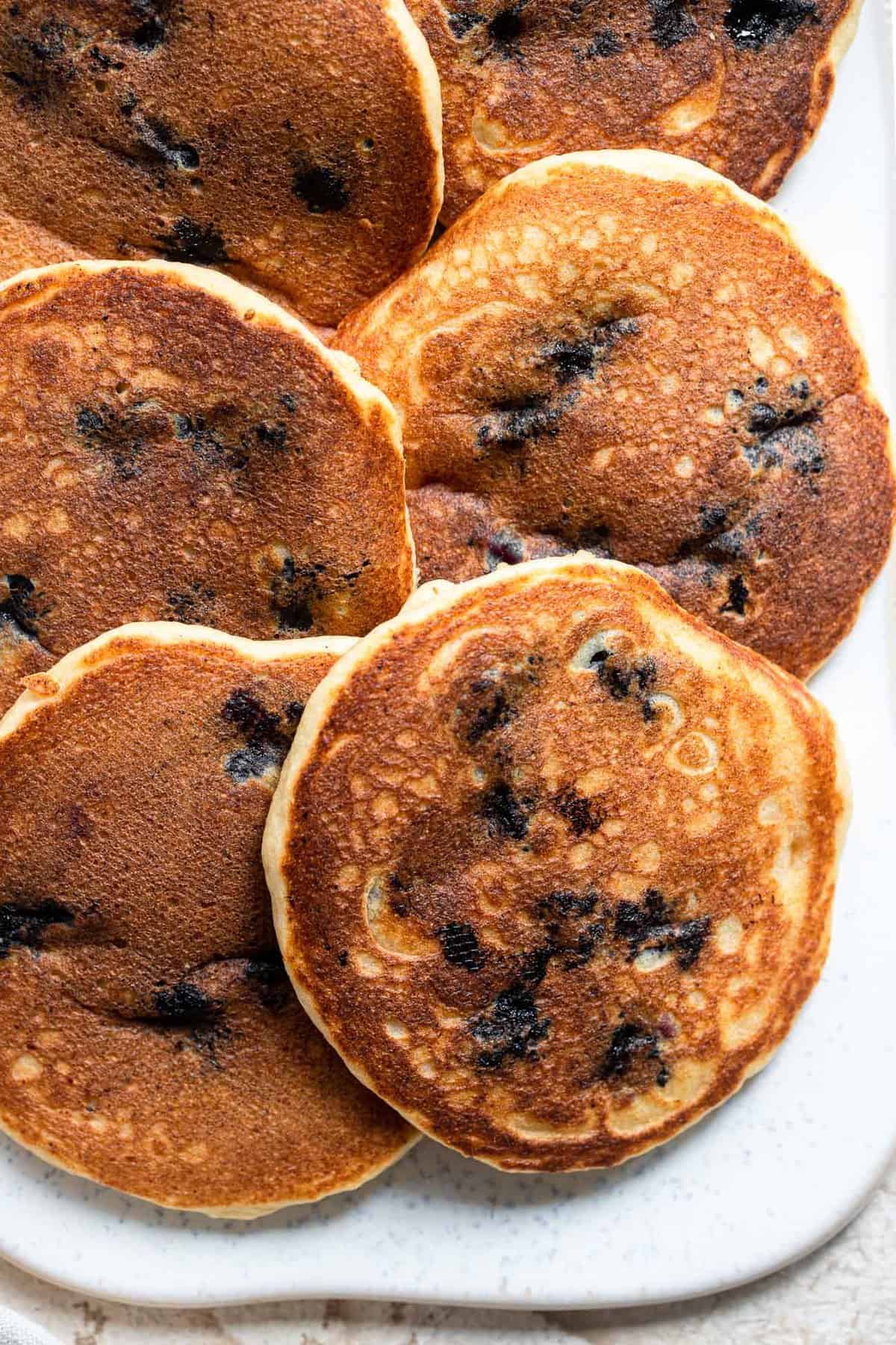 Whole Wheat Ricotta Blueberry Pancakes - These whole wheat blueberry pancakes are big, fluffy and creamy thanks to the addition of Ricotta Cheese! Easy, healthy and packed with protein! | #Foodfaithfitness | #glutenfree #healthy #wholewheat #pancakes Close up of Healthy blueberry pancakes on a plate