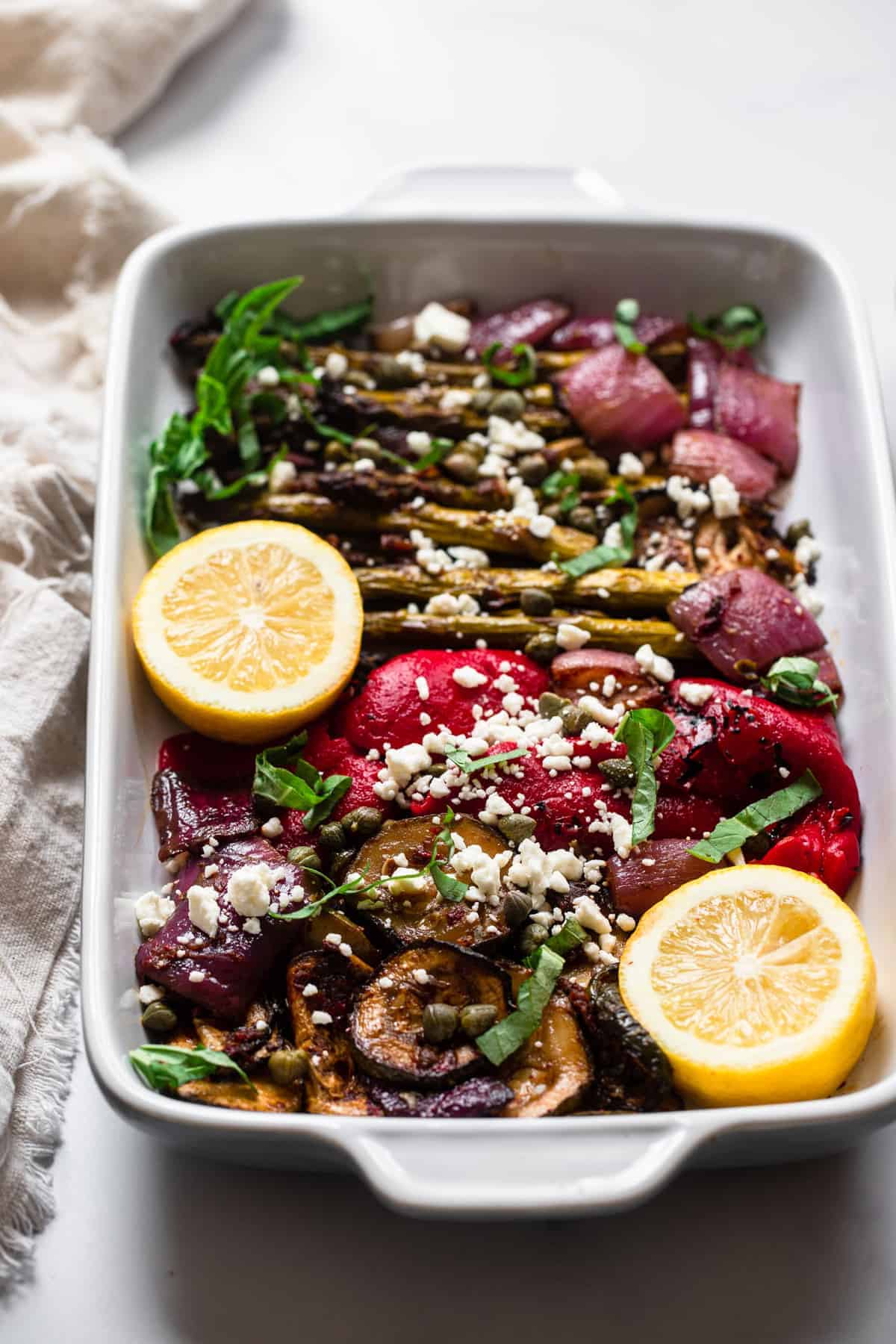 Balsamic Grilled Vegetable Salad - This quick and easy balsamic grilled vegetable salad is marinated in topped with sun dried tomatoes and feta cheese. Healthy, gluten free and delish! | #Foodfaithfitness | #glutenfree #healthy #grilled #salad #vegetarian Balsamic grilled vegetable salad in a baking dish with lemon on top