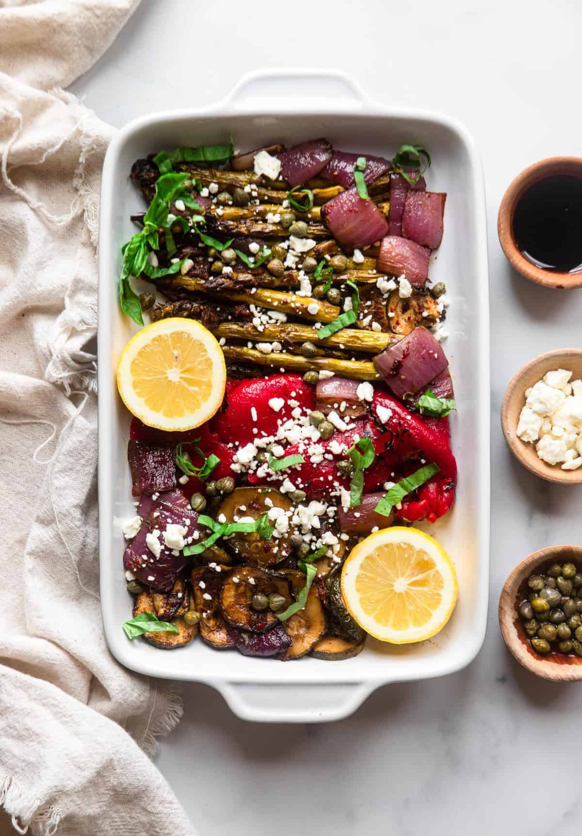 Balsamic Grilled Vegetable Salad - This quick and easy balsamic grilled vegetable salad is marinated in topped with sun dried tomatoes and feta cheese. Healthy, gluten free and delish! | #Foodfaithfitness | #glutenfree #healthy #grilled #salad #vegetarian serving dish with balsamic grilled vegetable salad inside with toppings on the side