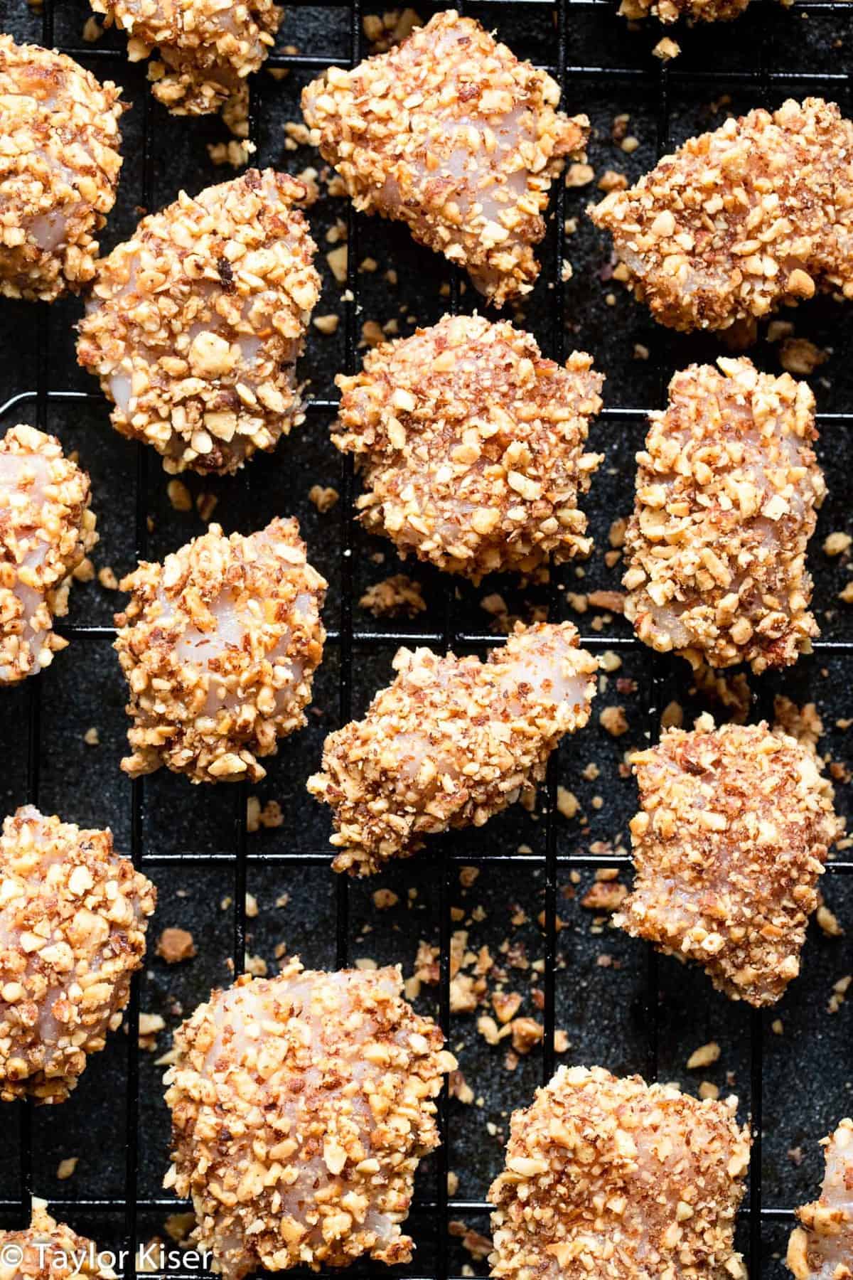 Low Carb Almond Crusted Chicken Bites - These Chicken Bites only take 20 minutes, and use 6 ingredients. They're baked, not fried, served with a healthy honey mustard dip and are a healthy dinner for the whole family! | #Foodfaithfitness | #Glutenfree #lowcarb #healthy #kidfriendly #dairyfree baked chicken bites on a baking sheet