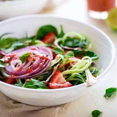Vegan Spiralized Cucumber Salad with Chia Strawberry Vinaigrette - This healthy cucumber salad recipe is mixed with fresh herbs, strawberries and a homemade lime-strawberry vinaigrette. It's a fresh, paleo & vegan meal for only 230 calories! | Foodfaithfitness.com | @FoodFaithFit