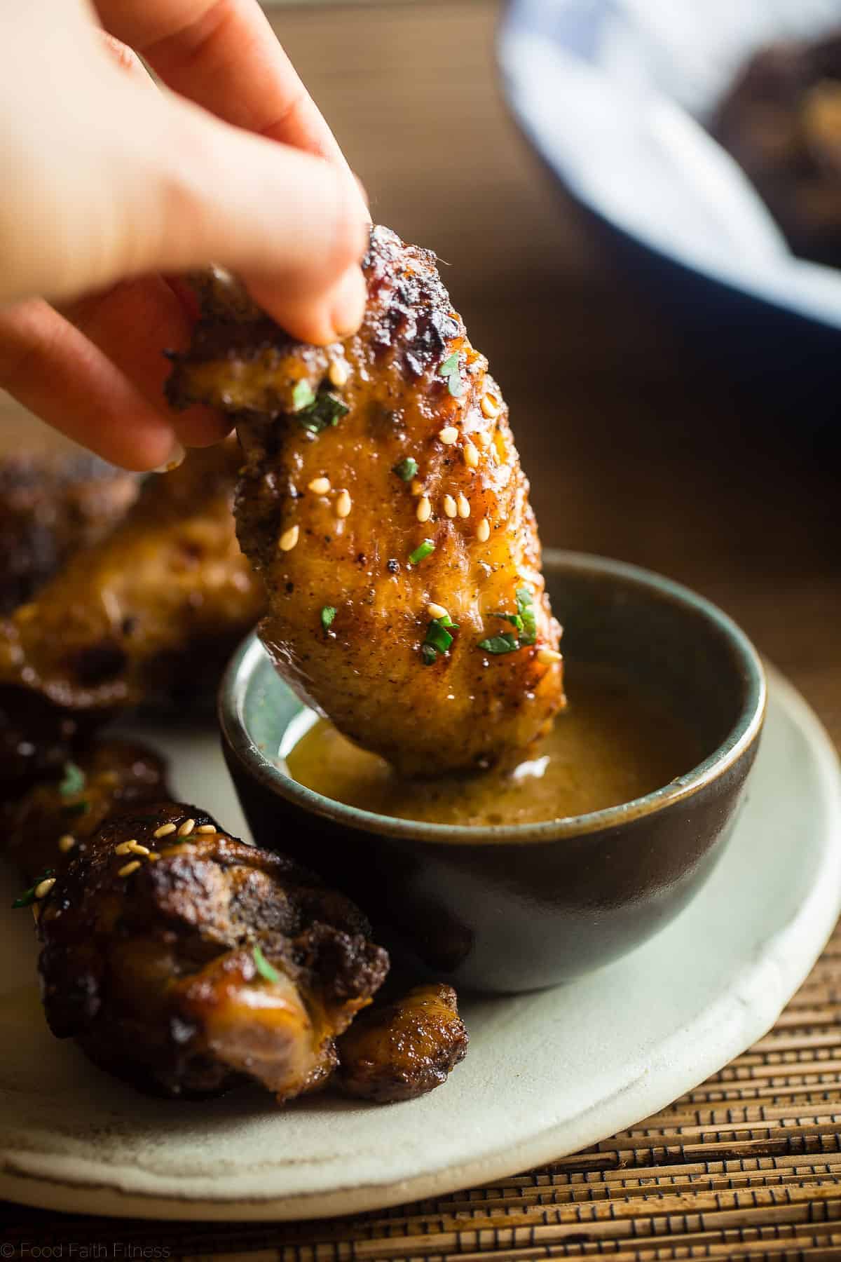 Sticky Asian Paleo Whole30 Chicken Wings - These sticky slow cooker Paleo Chicken wings are bursting with sweet and tangy Asian flavor! You'd never know they're a healthier, gluten free appetizer! | #Foodfaithfitness | #glutenfree #dairyfree #whole30 #paleo #healthy dipping paleo whole30 chicken wings in sauce