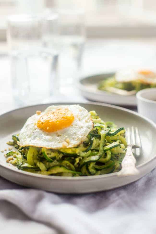zucchini noodles with pesto and a fried egg on a gray plate