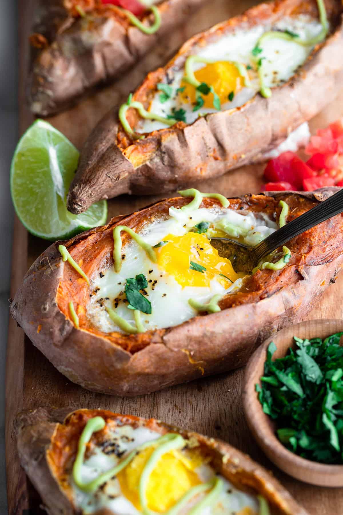 Twice Baked Mexican Sweet Potatoes - These Twice Baked Mexican Sweet Potatoes have a runny egg and a tangy lime avocado sauce! They're a healthy, gluten free and whole30 meal! | #Foodfaithfitness | #glutenfree #paleo #whole30 #healthy twice baked mexican sweet potatoes with eggs on a cutting board