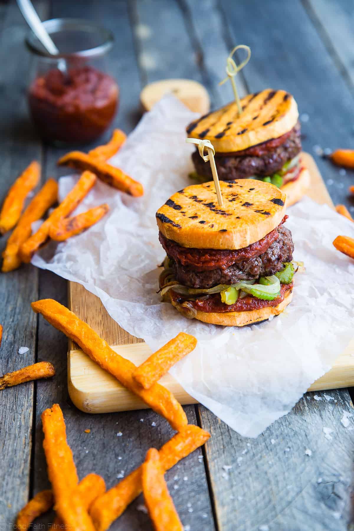 Healthy Cajun Burgers - These crowd-pleasing burgers use grilled sweet potatoes buns instead of bread! They're a healthy, whole30, gluten and dairy free summer meal for only 300 calories! | #Foodfaithfitness | #glutenfree #paleo #whole30 #healthy sweet potato bun cajun burger on a meat serving block with fries