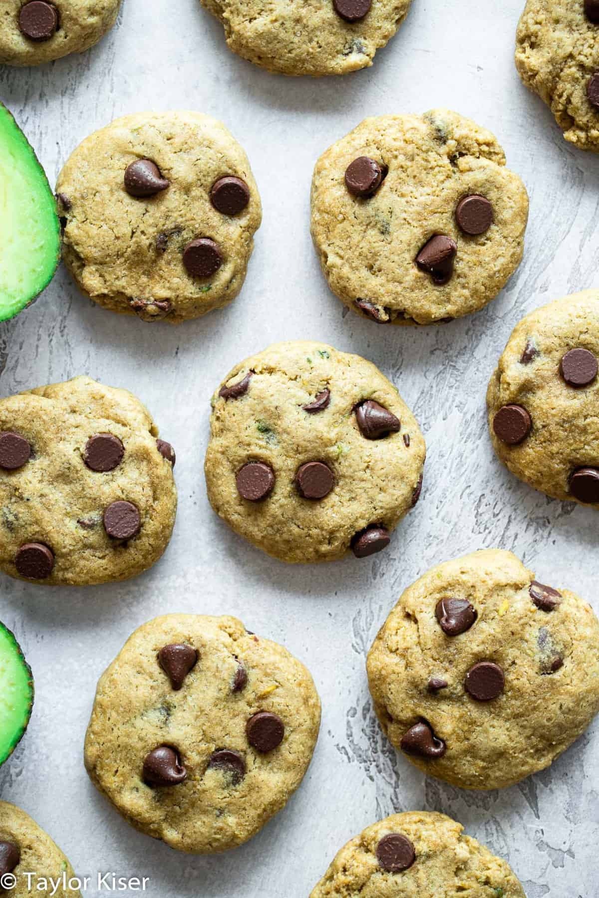 a bunch of Healthy Chocolate Chip Cookies next to raw avocados