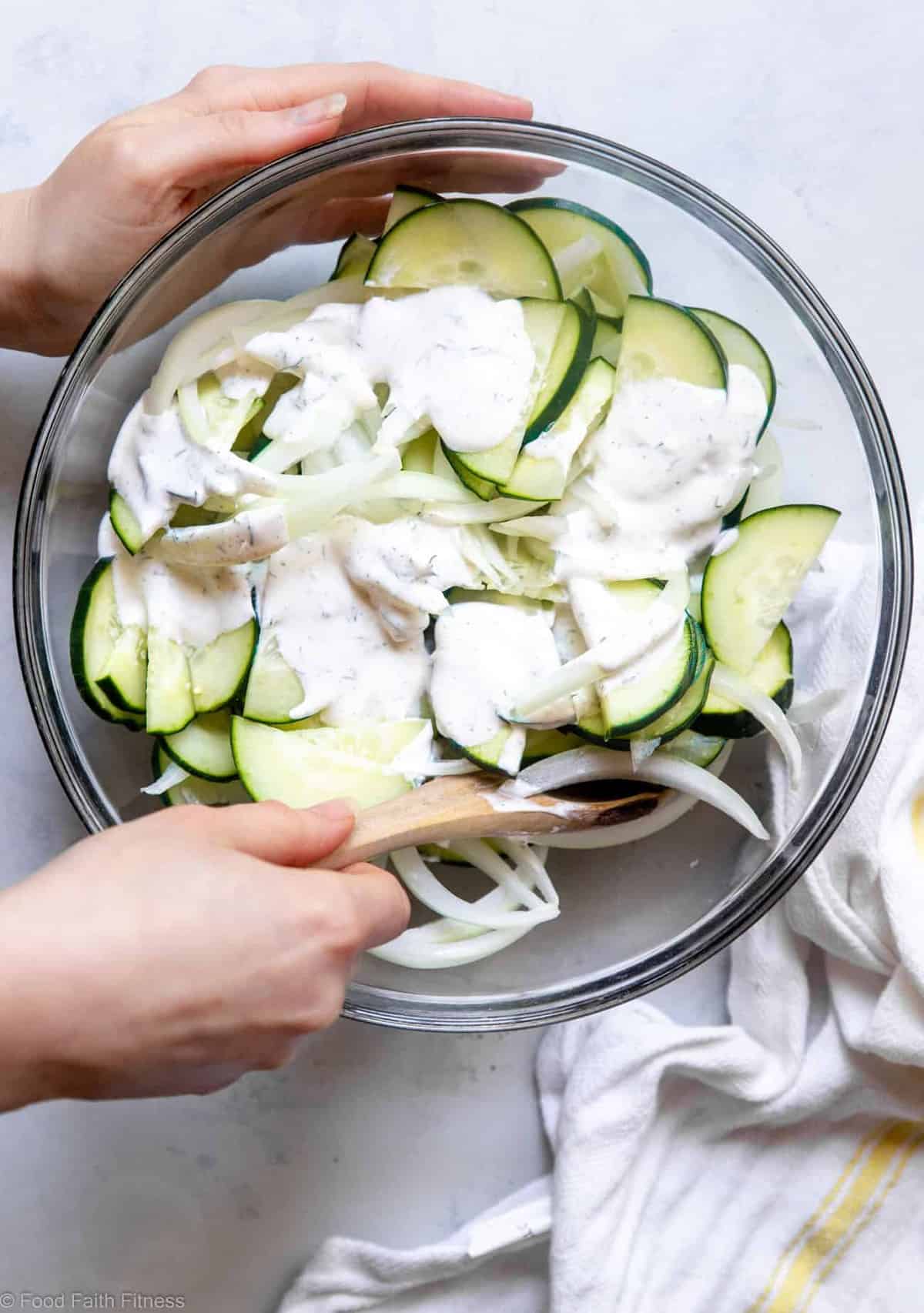 Low Carb Keto Cucumber Salad - An easy summer side that uses only 6 pantry essential ingredients! Creamy, naturally gluten free and only 50 calories! | #Foodfaithfitness | #Keto #Lowcarb #Glutenfree #Dairyfree #Sugarfree Person mixing a low carb cucumber salad recipe