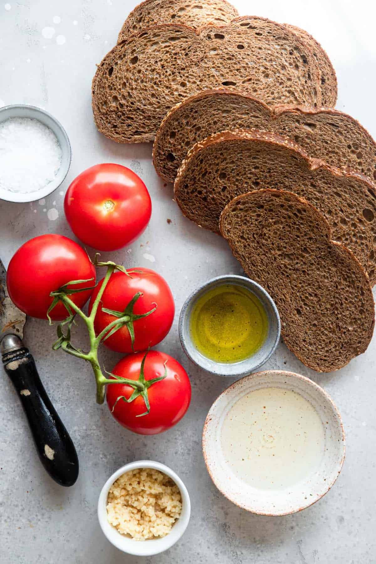 Pan Con Tomate - Tomato toast is a traditional Spanish breakfast that is made from 4 simple, healthy ingredients and has big flavor! This will be your new go to breakfast! Naturally Paleo, low carb and vegan too! | #Foodfaithfitness | #Glutenfree #Paleo #Lowcarb #Vegan #sugarfree ingredients to make a pan con tomate recipe on a table