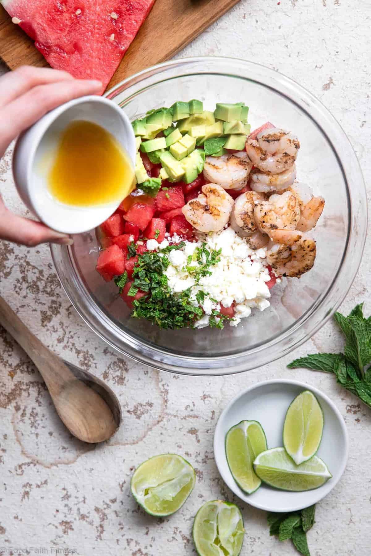 Pouring dressing onto a shrimp avocado salad with watermelon