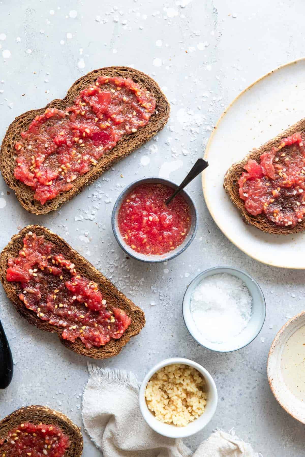 Pan Con Tomate - Tomato toast is a traditional Spanish breakfast that is made from 4 simple, healthy ingredients and has big flavor! This will be your new go to breakfast! Naturally Paleo, low carb and vegan too! | #Foodfaithfitness | #Glutenfree #Paleo #Lowcarb #Vegan #sugarfree Spanish tomato bread on a table
