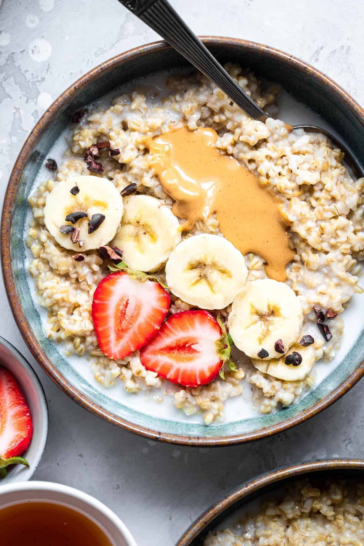 Instant Pot Steel Cut Oats - a quick, simple breakfast that are only 2 ingredients! Naturally gluten free, vegan, healthy and SO filling! Great for meal prep too! | #Foodfaithfitness | #Glutenfree #vegan #healthy #sugarfree #dairyfree #Instantpot cooked instant pot steel cut oats in a bowl with strawberries and bananas
