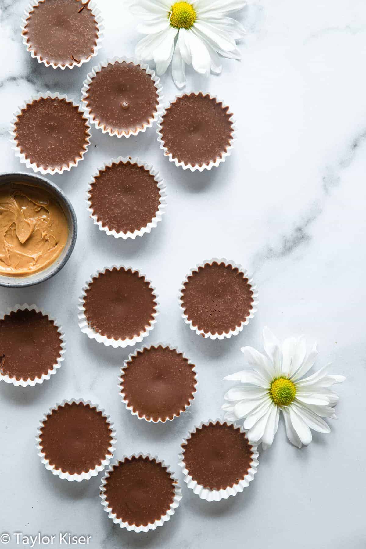 No Bake Keto Chocolate Peanut Butter Fat Bombs - These No Bake Fat Bombs are an easy, 4 ingredient dessert that are sugar free, gluten free and low carb! Delicious and simple even if you're not keto! | #Foodfaithfitness | #glutenfree #lowcarb #sugarfree #keto #healthy chocolate keto fat bombs on a table with flowers