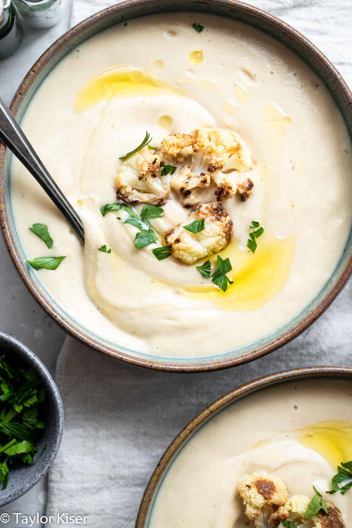 Vegan Cauliflower Soup - This creamy, dairy free and vegan roasted cauliflower soup is SO easy to make and great for cold nights! Naturally low carb, gluten free and healthy too! | #Foodfaithfitness | #Glutenfree #vegan #healthy #lowcarb #keto close up of vegan cauliflower soup in a bowl