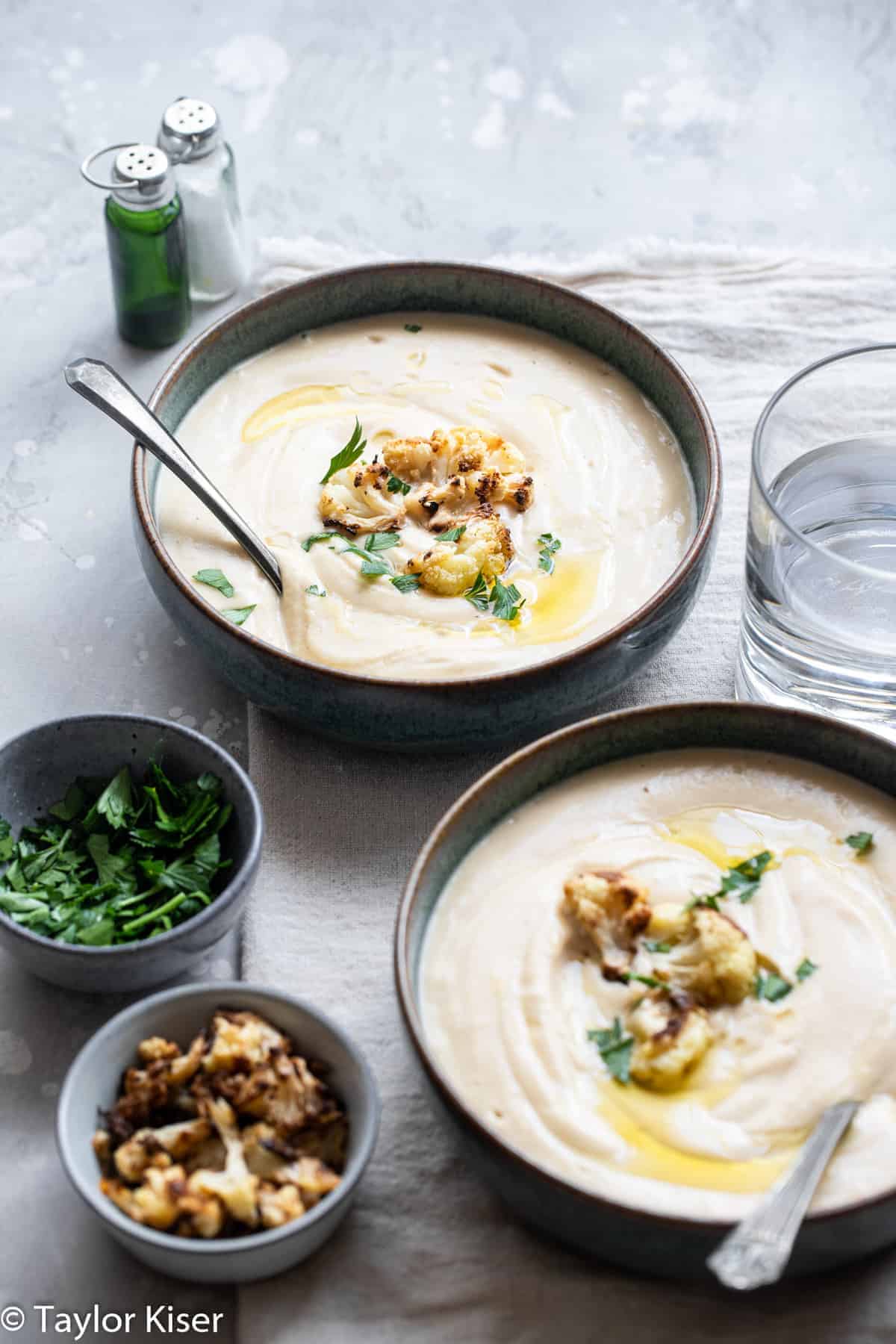 Vegan Cauliflower Soup - This creamy, dairy free and vegan roasted cauliflower soup is SO easy to make and great for cold nights! Naturally low carb, gluten free and healthy too! | #Foodfaithfitness | #Glutenfree #vegan #healthy #lowcarb #keto two bowls of keto cauliflower soup with spoons in them