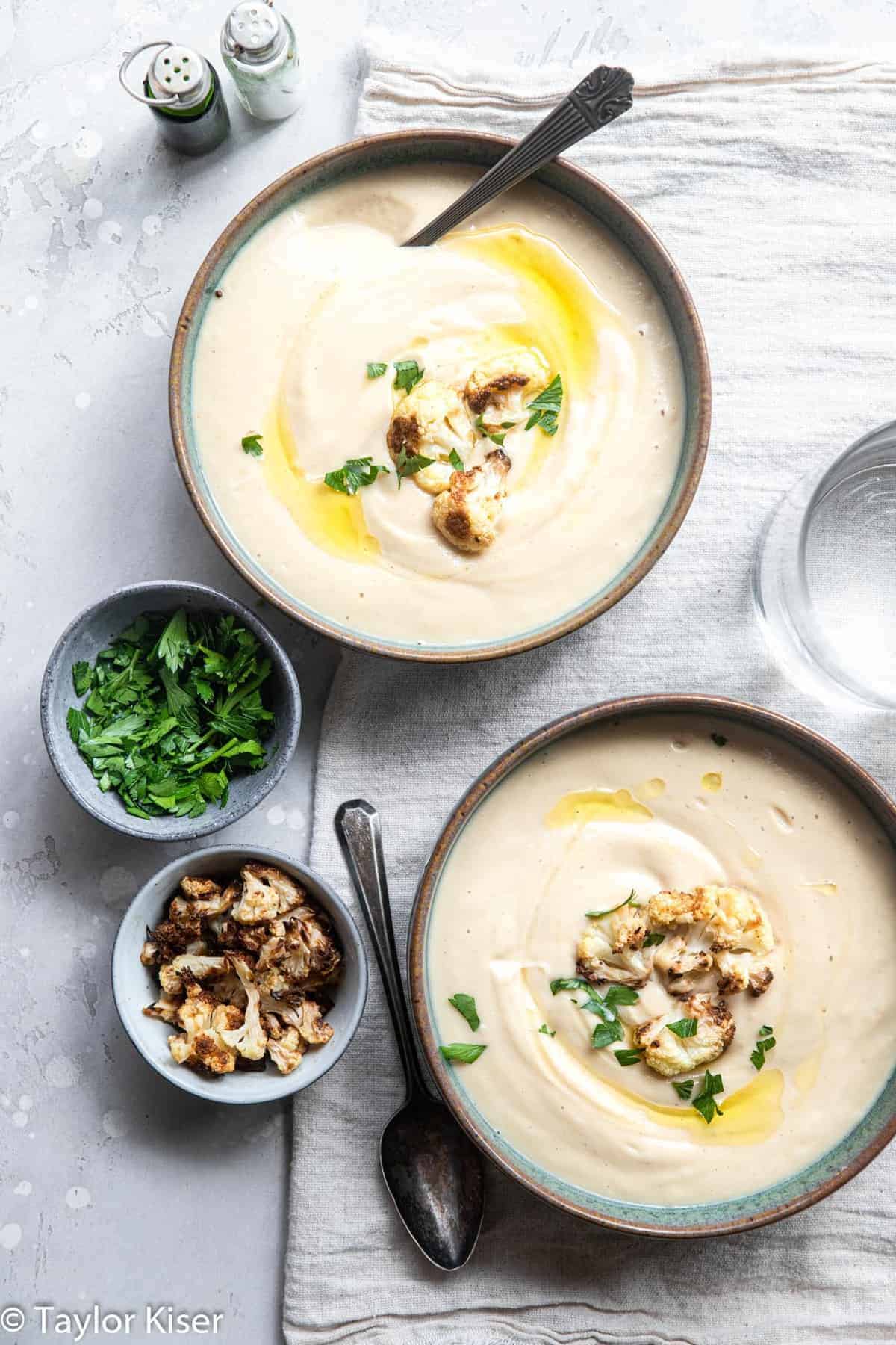 Vegan Cauliflower Soup - This creamy, dairy free and vegan roasted cauliflower soup is SO easy to make and great for cold nights! Naturally low carb, gluten free and healthy too! | #Foodfaithfitness | #Glutenfree #vegan #healthy #lowcarb #keto close up of two bowls of low carb cauliflower soup