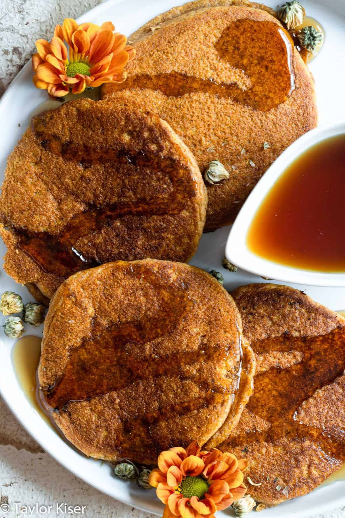 Whole Wheat Healthy Pumpkin Cakes - These dairy and egg free pancakes are light, fluffy and perect for fall! You will never believe they are better for you and so easy to make! | #Foodfaithfitness | #vegan #healthy #eggfree #dairyfree #wholewheat easy pumpkin pancakes layed out on a plate