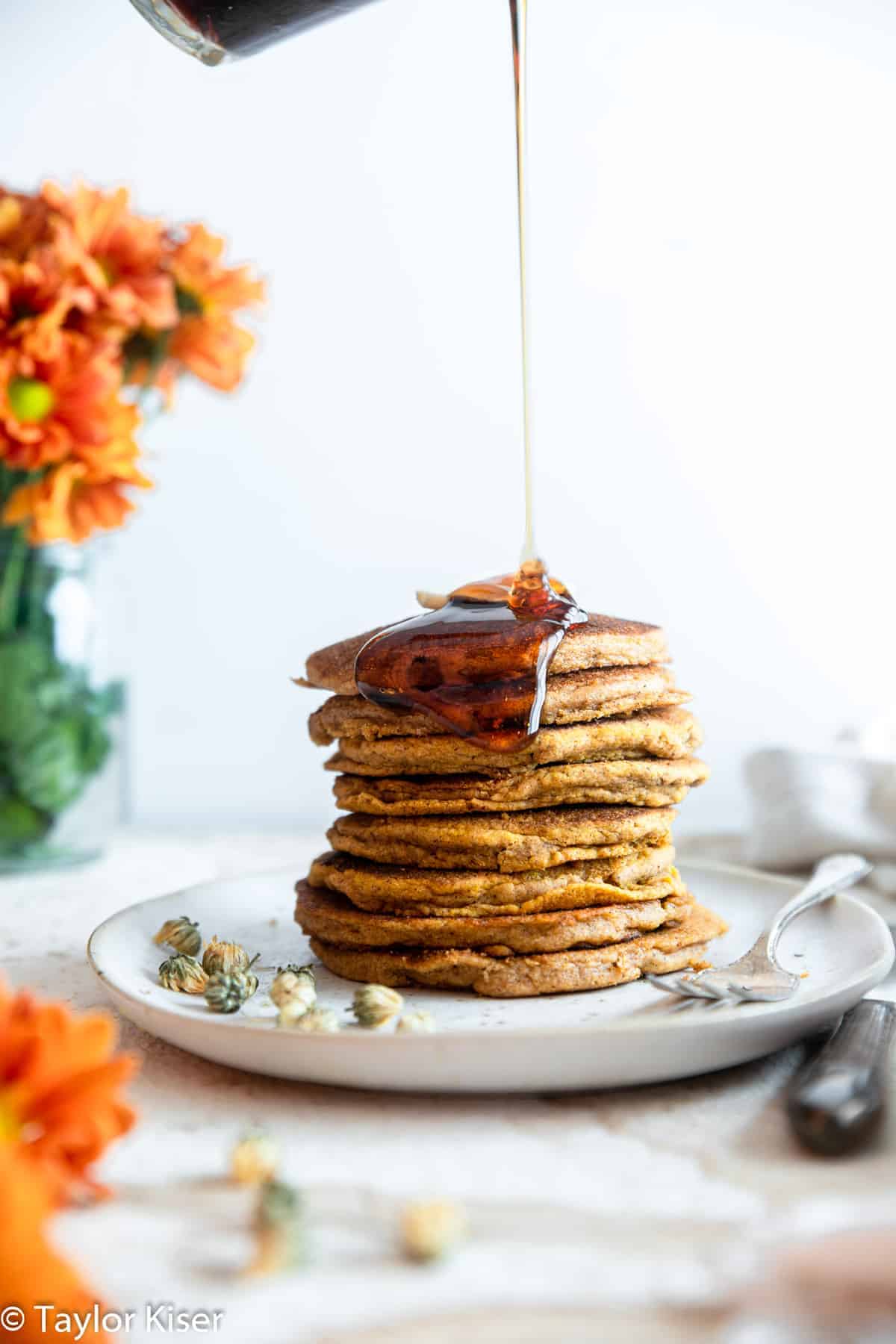 Whole Wheat Healthy Pumpkin Cakes - These dairy and egg free pancakes are light, fluffy and perect for fall! You will never believe they are better for you and so easy to make! | #Foodfaithfitness | #vegan #healthy #eggfree #dairyfree #wholewheat whole wheat pumpkin pancakes with syrup drizzling on them