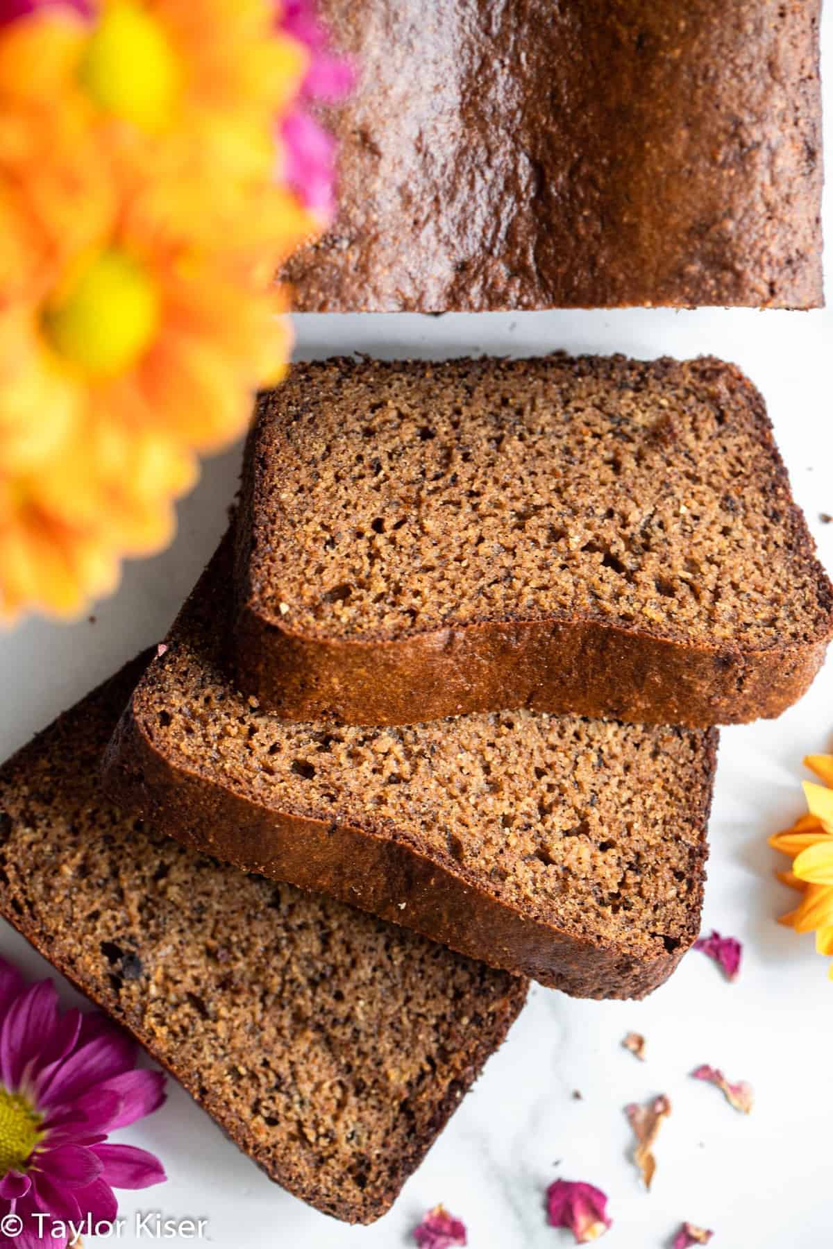 High Protein Banana Bread - This easy banana bread is naturally gluten free and packed with protein! Moist, tender, easy to make and so delicious! The best snack or breakfast! | #Foodfaithfitness | #Glutenfree #healthy #proteinpowder #paleo #grainfree Slices of protein banana bread with flowers on a table