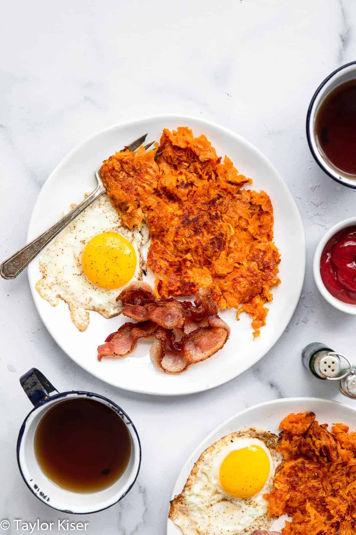 Easy Sweet Potato Hash Browns - These shredded Sweet Potato Hash Browns are easy and better than store bought! Naturally gluten free and healthy! Learn the secrets to making them crispy too! | #Foodfaithfitness | #glutenfree #paleo #healthy #whole30 #dairyfree sweet potato hash browns on a plate with bacon and eggs