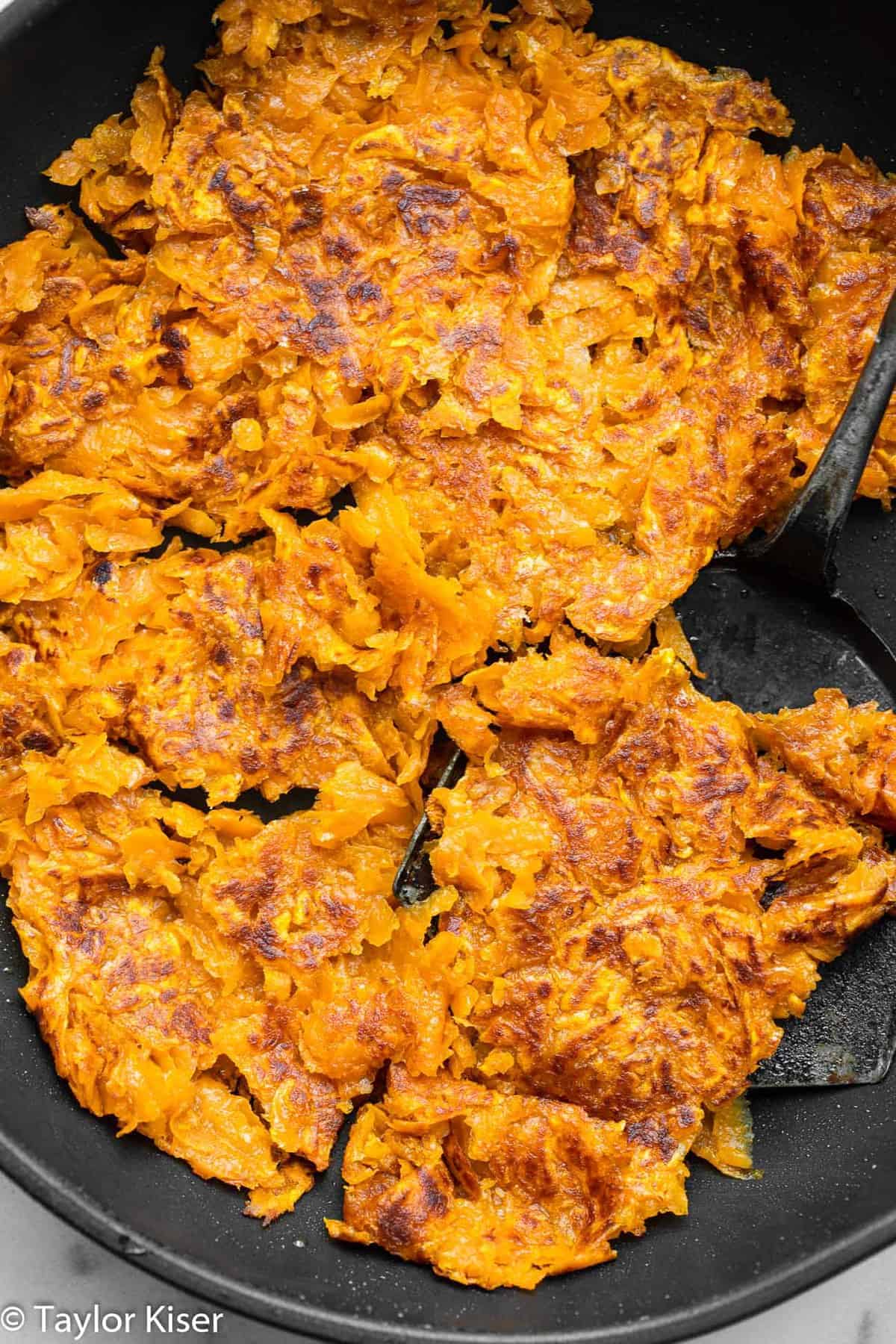 Easy Sweet Potato Hash Browns - These shredded Sweet Potato Hash Browns are easy and better than store bought! Naturally gluten free and healthy! Learn the secrets to making them crispy too! | #Foodfaithfitness | #glutenfree #paleo #healthy #whole30 #dairyfree sweet potato hash browns cooking in a skillet
