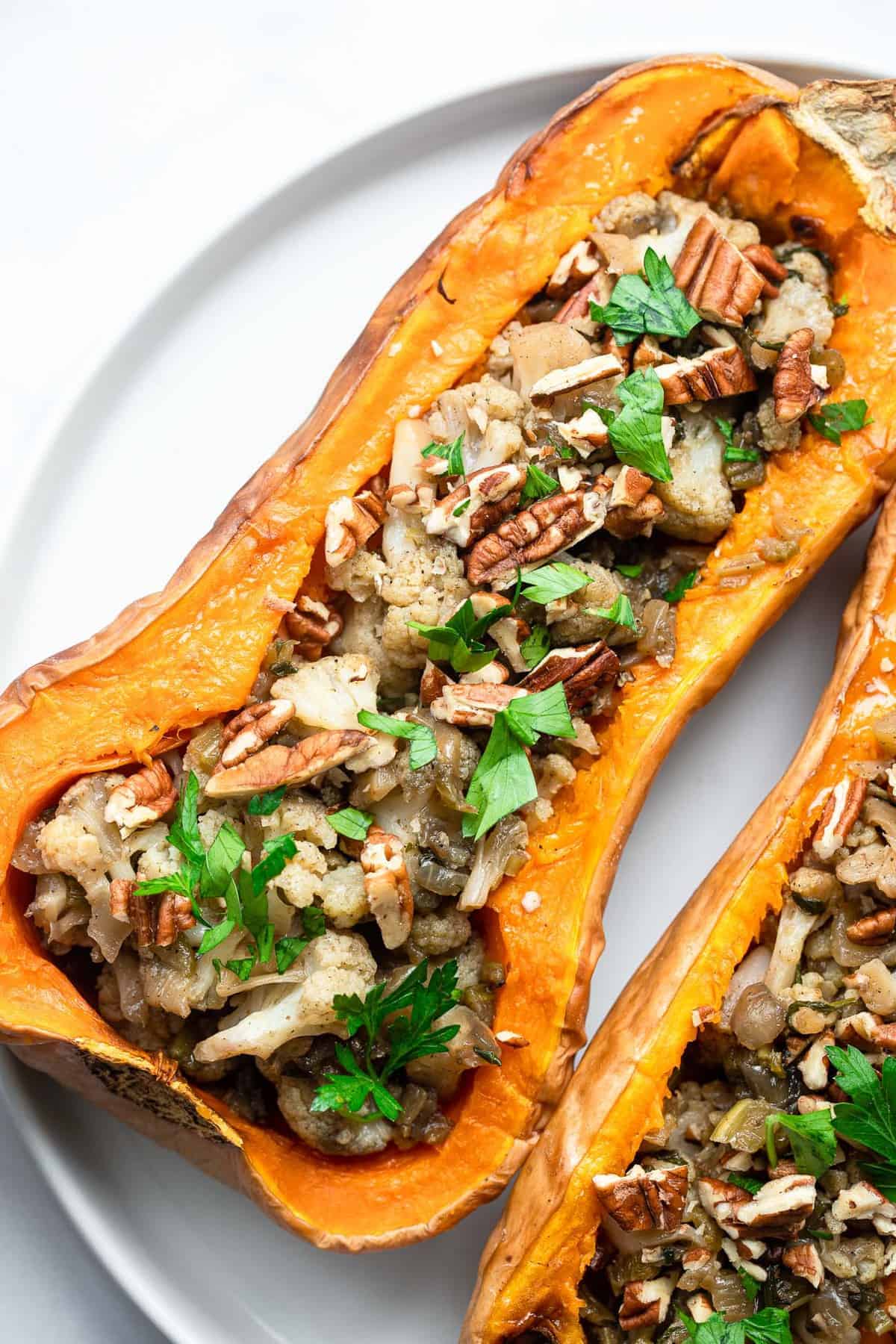 Vegan Stuffed Butternut Squash - An easy, fall dinner or side dish that is loaded with cozy, flavors and is very easy to make! Gluten free, paleo and whole30 friendly too! | #Foodfaithfitness | #glutenfree #vegan #paleo #whole30 #dairyfree close up of vegan stuffed squash with cauliflower