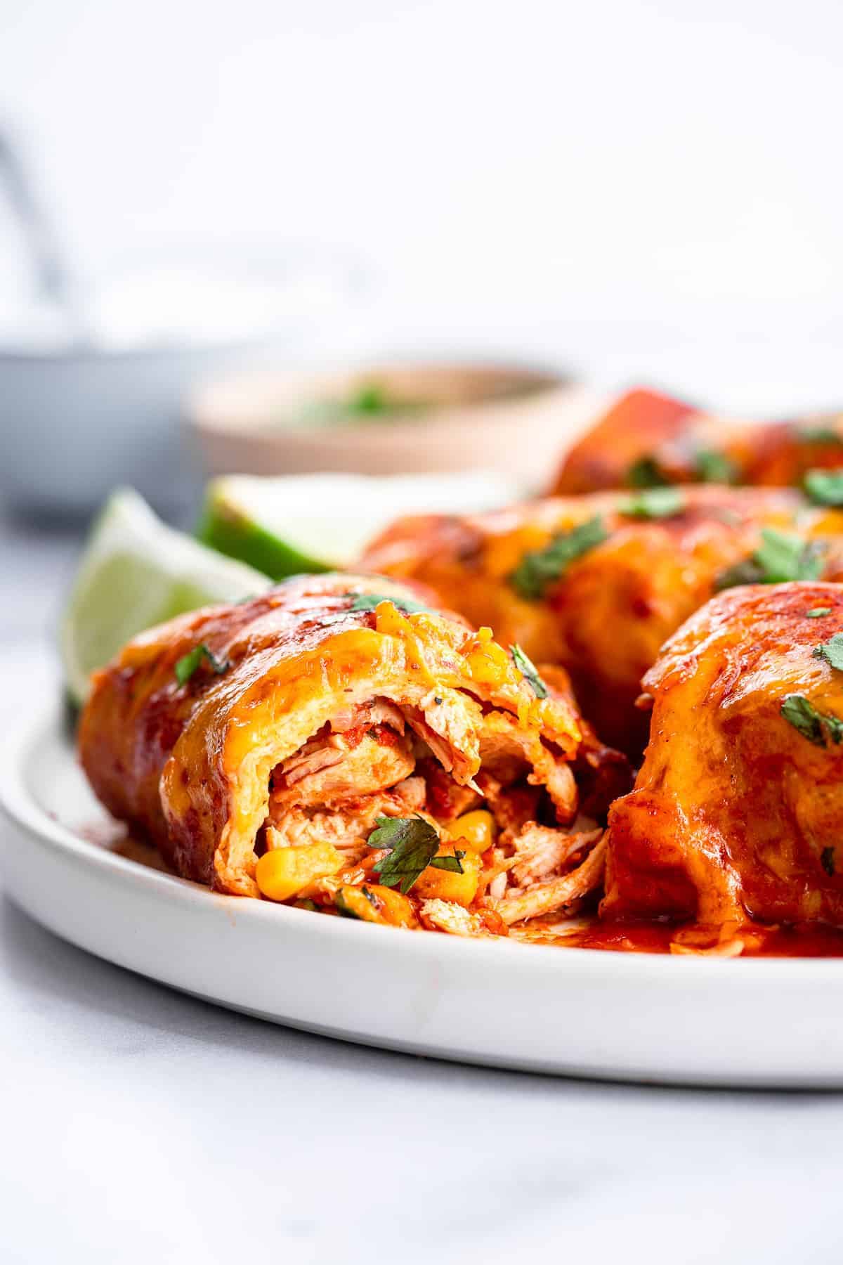 Healthy Crock Pot Chicken Enchiladas - an easy, healthy weeknight dinner that the whole family will love - even picky eaters! Makes great leftovers and freezer meals too! | #Foodfaithfitness | #healthy #dinner #slowcooker #crockpot #kidfriendly crock pot chicken enchiladas cut open on a plate