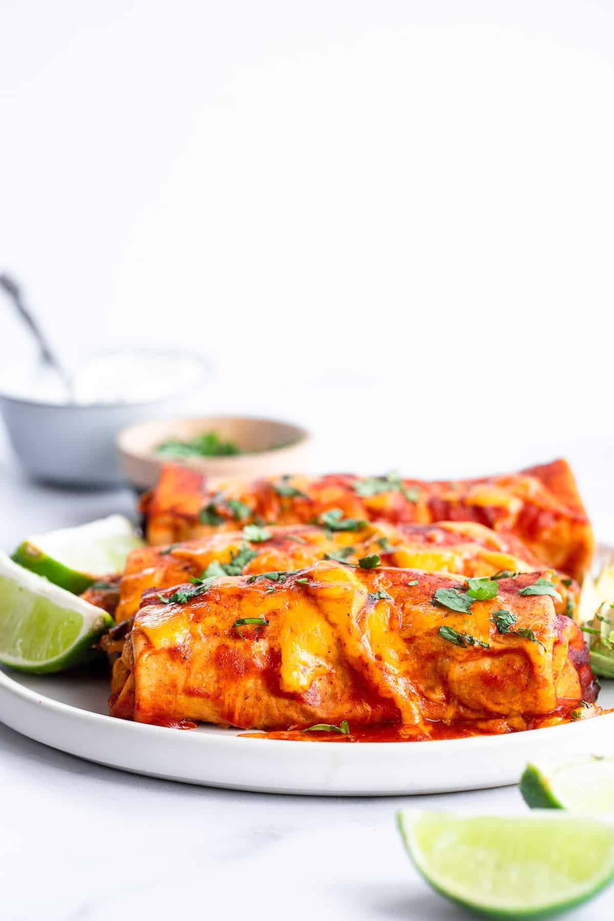 Healthy Crock Pot Chicken Enchiladas - an easy, healthy weeknight dinner that the whole family will love - even picky eaters! Makes great leftovers and freezer meals too! | #Foodfaithfitness | #healthy #dinner #slowcooker #crockpot #kidfriendly 3 crockpot enchiladas on a plate