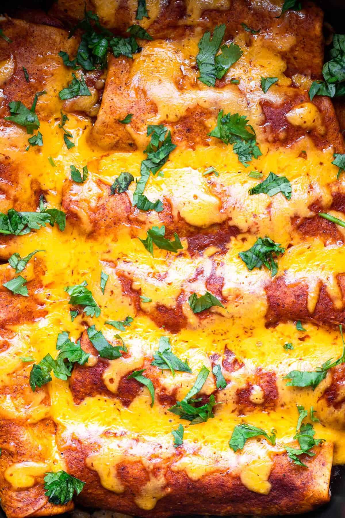 Healthy Crock Pot Chicken Enchiladas - an easy, healthy weeknight dinner that the whole family will love - even picky eaters! Makes great leftovers and freezer meals too! | #Foodfaithfitness | #healthy #dinner #slowcooker #crockpot #kidfriendly close up on slow cooker chicken enchiladas