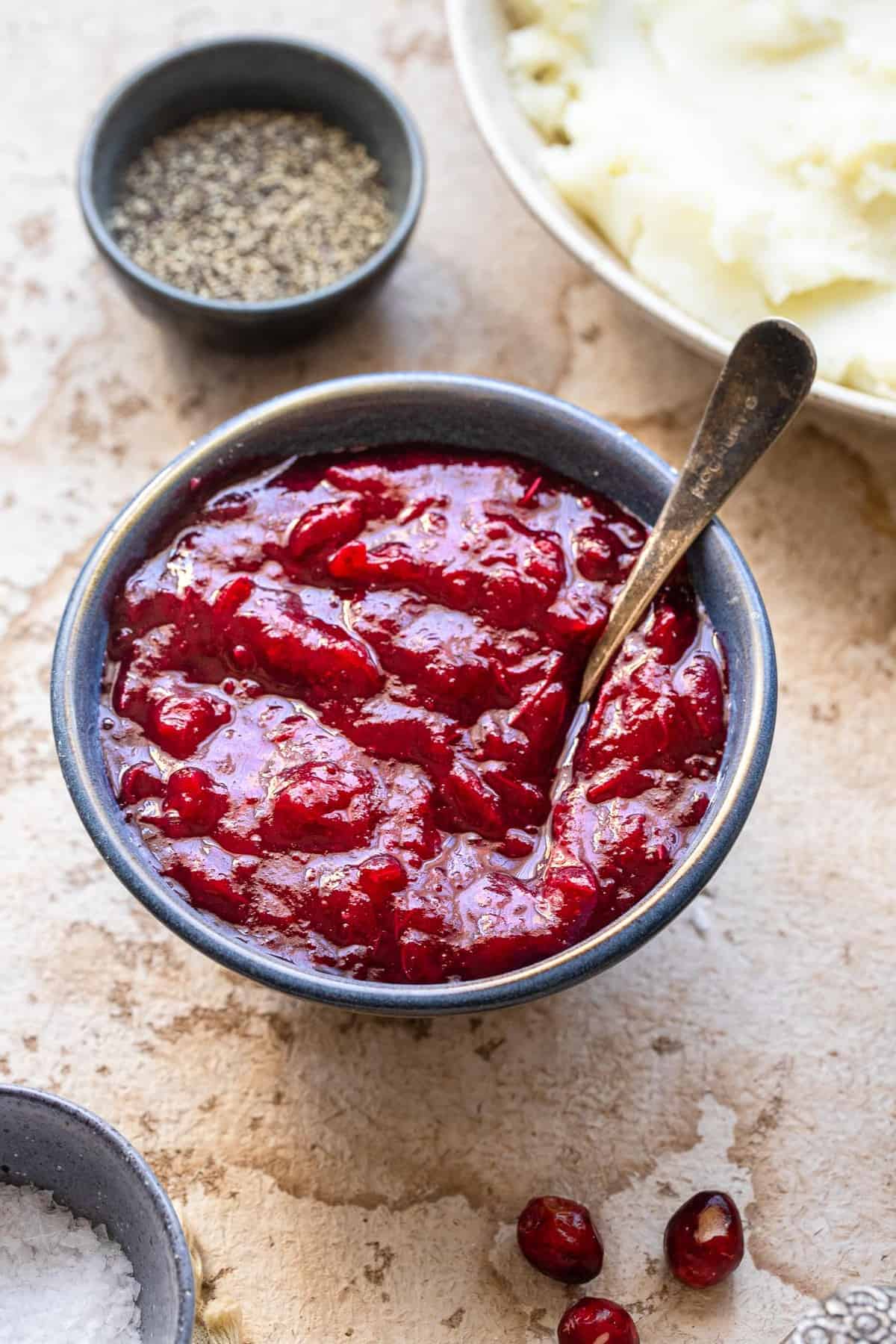 Low Carb Sugar Free Keto Cranberry Sauce - this Keto Cranberry Sauce is only 3 ingredients and SO easy to make! It's better than store bought, naturally gluten free and healthy! | #Foodfaithfitness | #glutenfree #paleo #keto #sugarfree #lowcarb low carb keto cranberry sauce in a blue bowl with a spoon