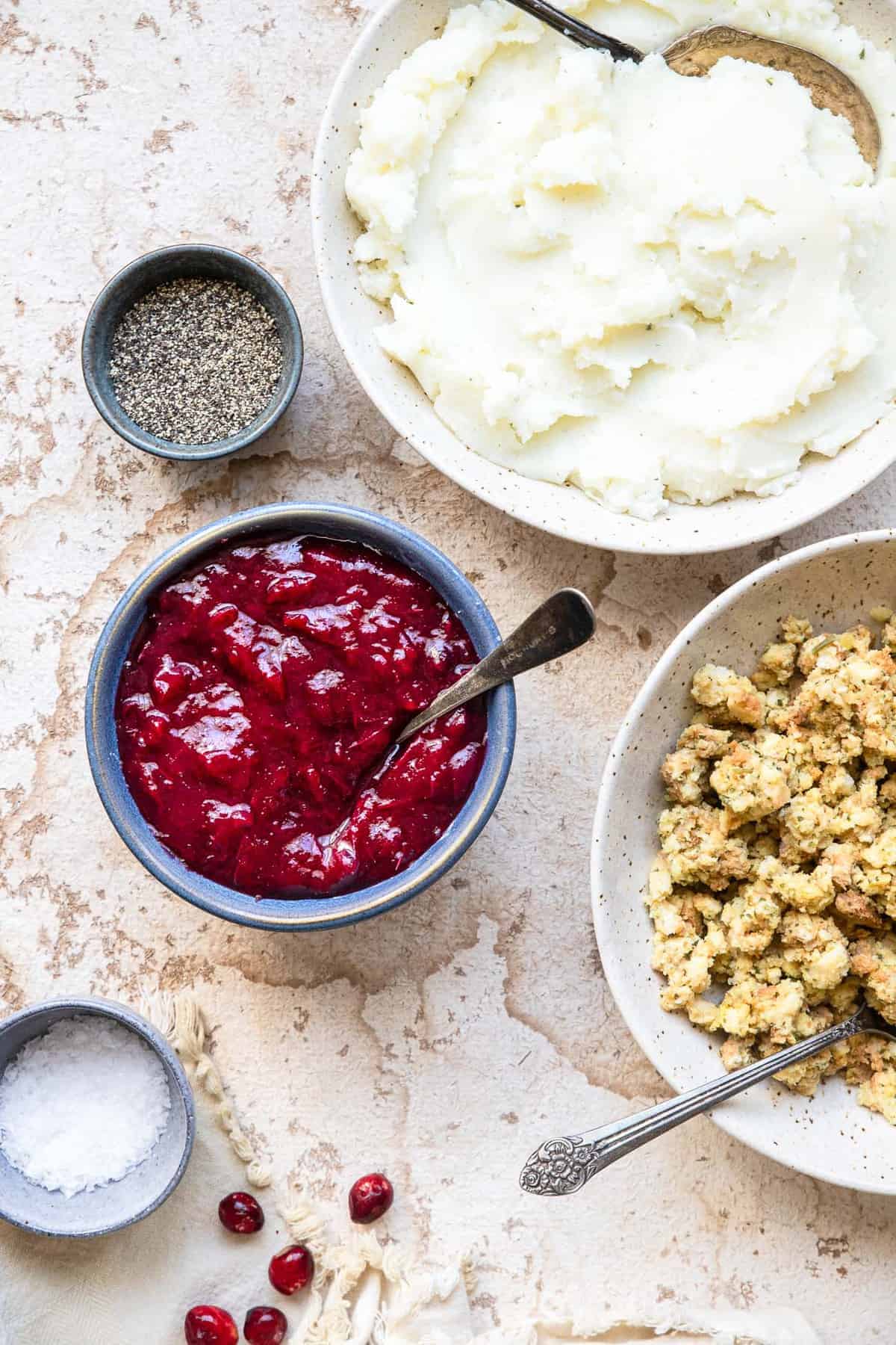 Low Carb Sugar Free Keto Cranberry Sauce - this Keto Cranberry Sauce is only 3 ingredients and SO easy to make! It's better than store bought, naturally gluten free and healthy! | #Foodfaithfitness | #glutenfree #paleo #keto #sugarfree #lowcarb sugar free cranberry sauce on a table with stuffing and mashed potatoes