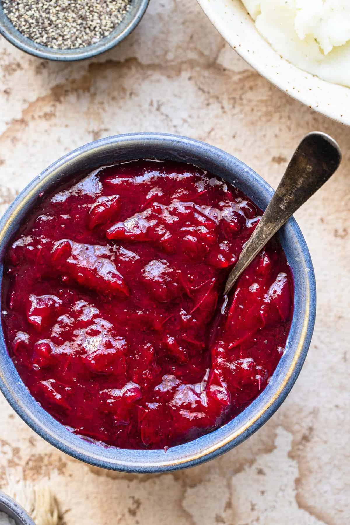 Low Carb Sugar Free Keto Cranberry Sauce - this Keto Cranberry Sauce is only 3 ingredients and SO easy to make! It's better than store bought, naturally gluten free and healthy! | #Foodfaithfitness | #glutenfree #paleo #keto #sugarfree #lowcarb Low carb cranberry sauce in a blue bowl