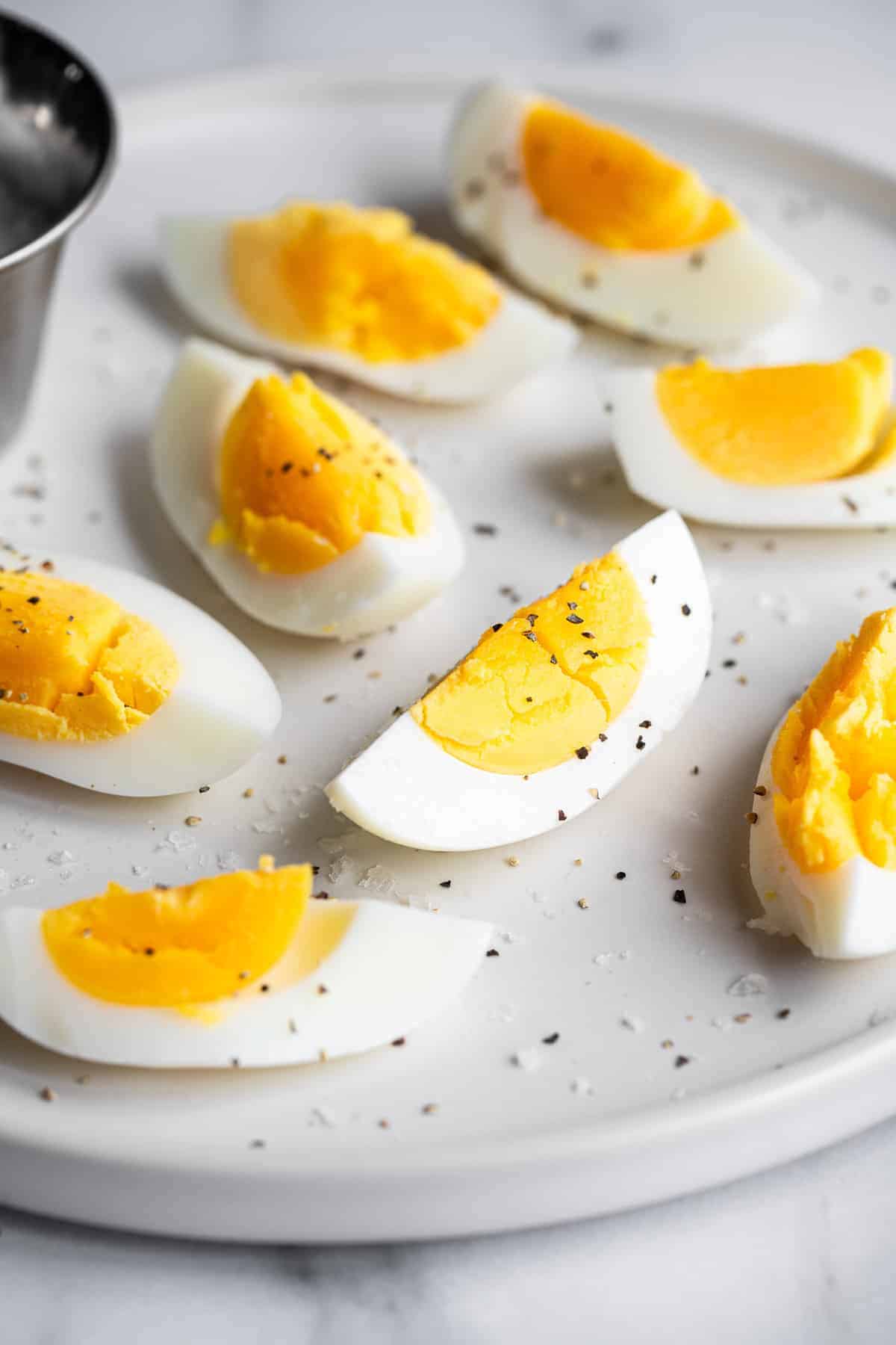 Air Fryer Hard Boiled Eggs - These 1 ingredient air fryer hard boiled eggs are even easier than boiling them and come out perfect every time! Gluten free, keto, paleo, low carb and healthy! The perfect snack or addition to a meal! | #Foodfaithfitness | #airfryer #glutenfree #keto #paleo #lowcarb sliced air fryer hard boiled eggs with pepper on them