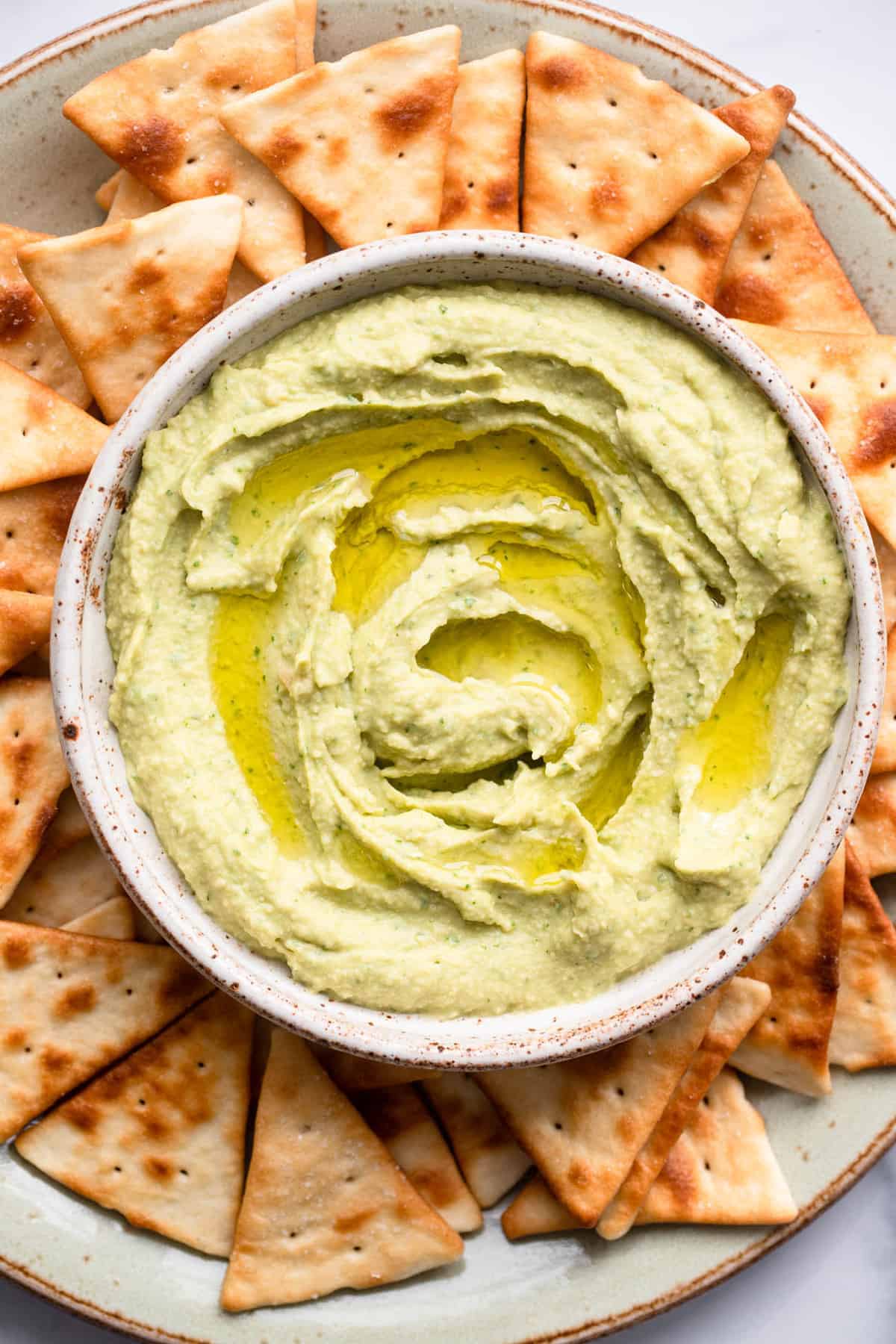 Avocado Hummus Recipe in a bowl with chips and olive oil