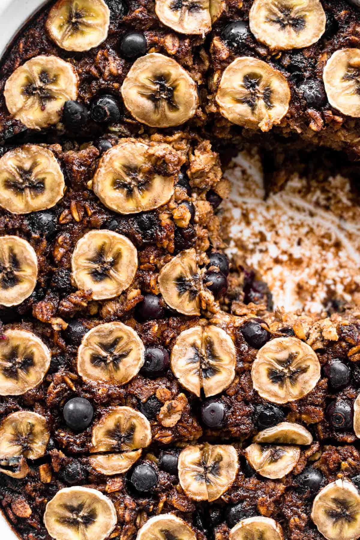 Baked oatmeal with blueberries and banana in a baking dish with slice missing