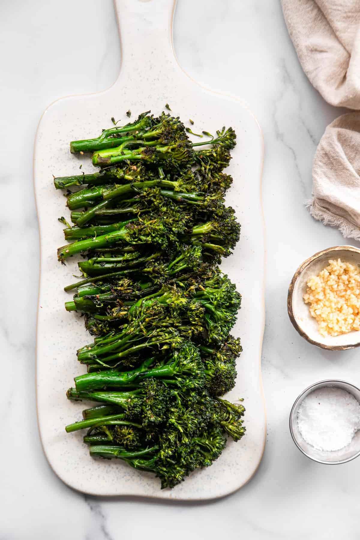 Sautéed broccolini on a plate with seasonings on the side