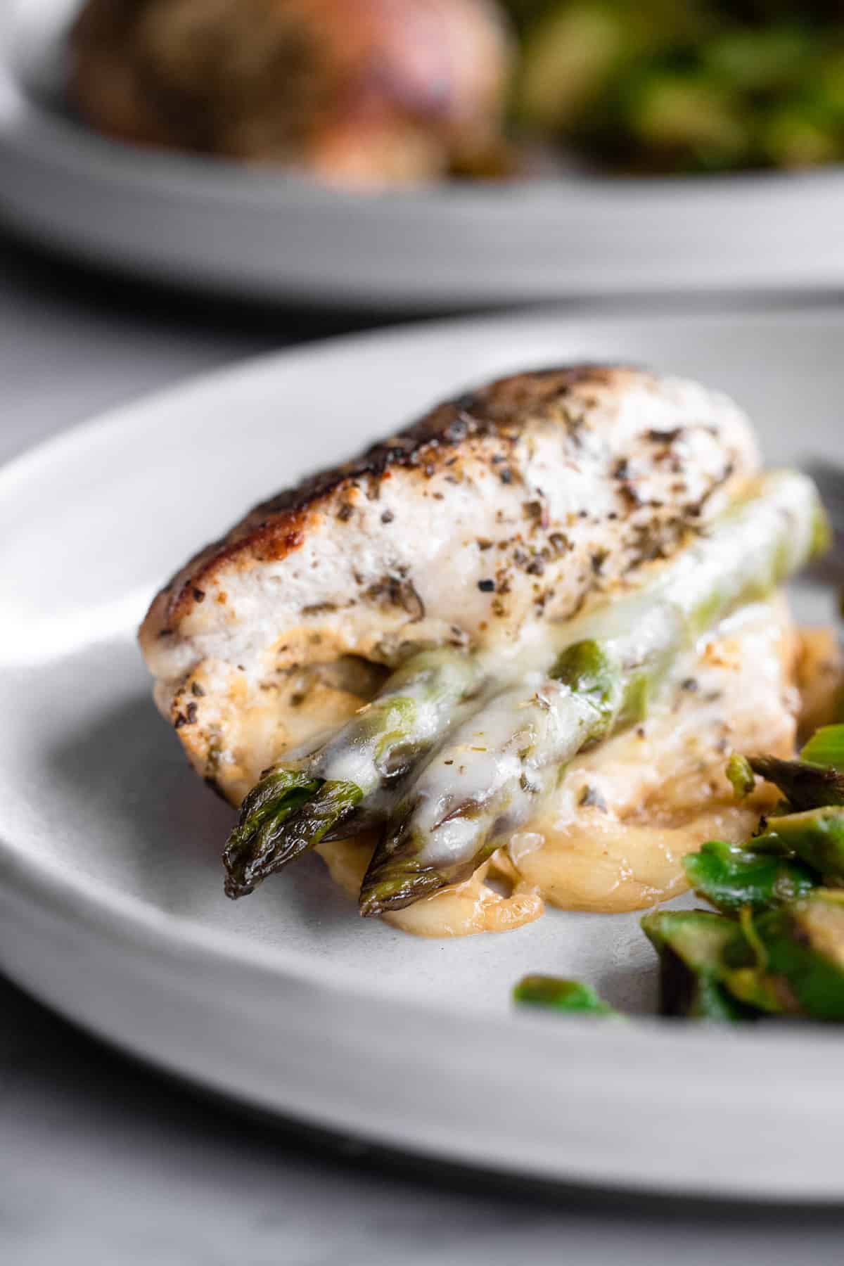Low Carb Asparagus Stuffed Chicken - This Asparagus Stuffed Chicken Breast is a super easy meal that feels fancy! Naturally gluten free, low carb, healthy and tasty too! | #Foodfaithfitness | #lowcarb #keto #glutenfree #healthy Stuffed chicken and asparagus on a plate close up