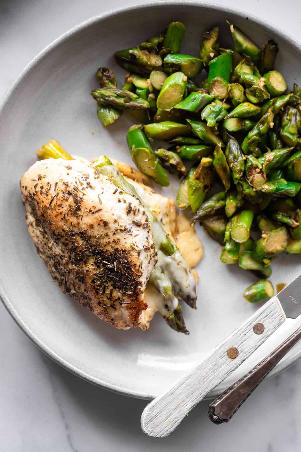 Low Carb Asparagus Stuffed Chicken - This Asparagus Stuffed Chicken Breast is a super easy meal that feels fancy! Naturally gluten free, low carb, healthy and tasty too! | #Foodfaithfitness | #lowcarb #keto #glutenfree #healthy asparagus stuffed chicken on a plate with asparagus stir fry