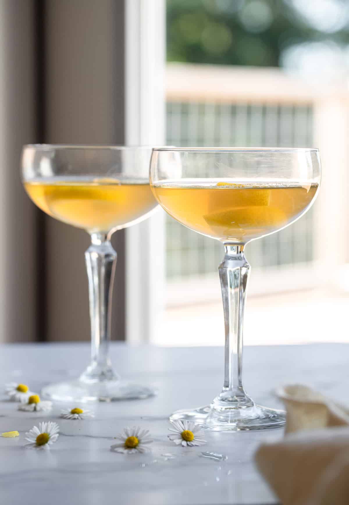 Bees Knees Cocktail - This Bees Knees Cocktail recipe is only 3 simple ingredients and is the perfect, light Summer cocktail! Naturally gluten free, refined sugar free and tasty! | #Foodfaithfitness | #glutenfree #healthy #cocktail two bees knees cocktails on a table in cocktail glasses