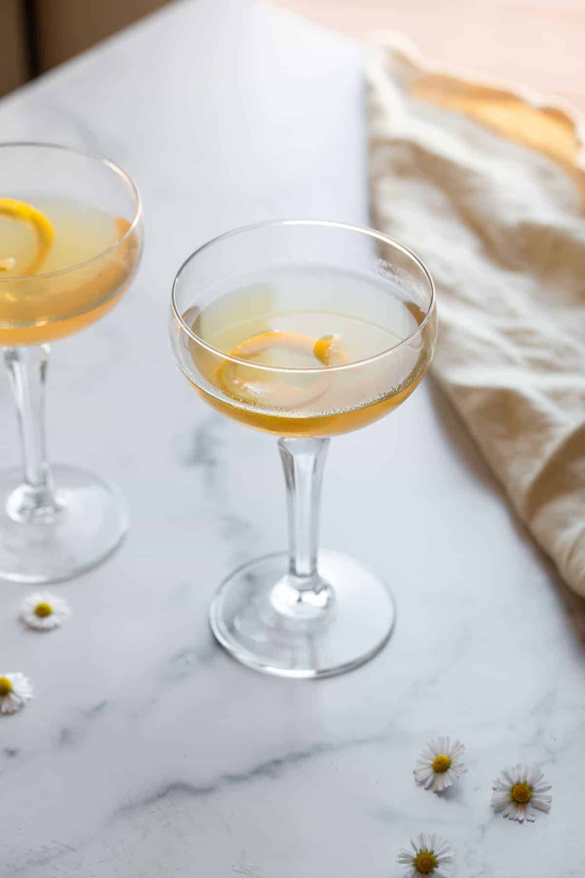 side view of bees knees cocktail with lemon peel in glass