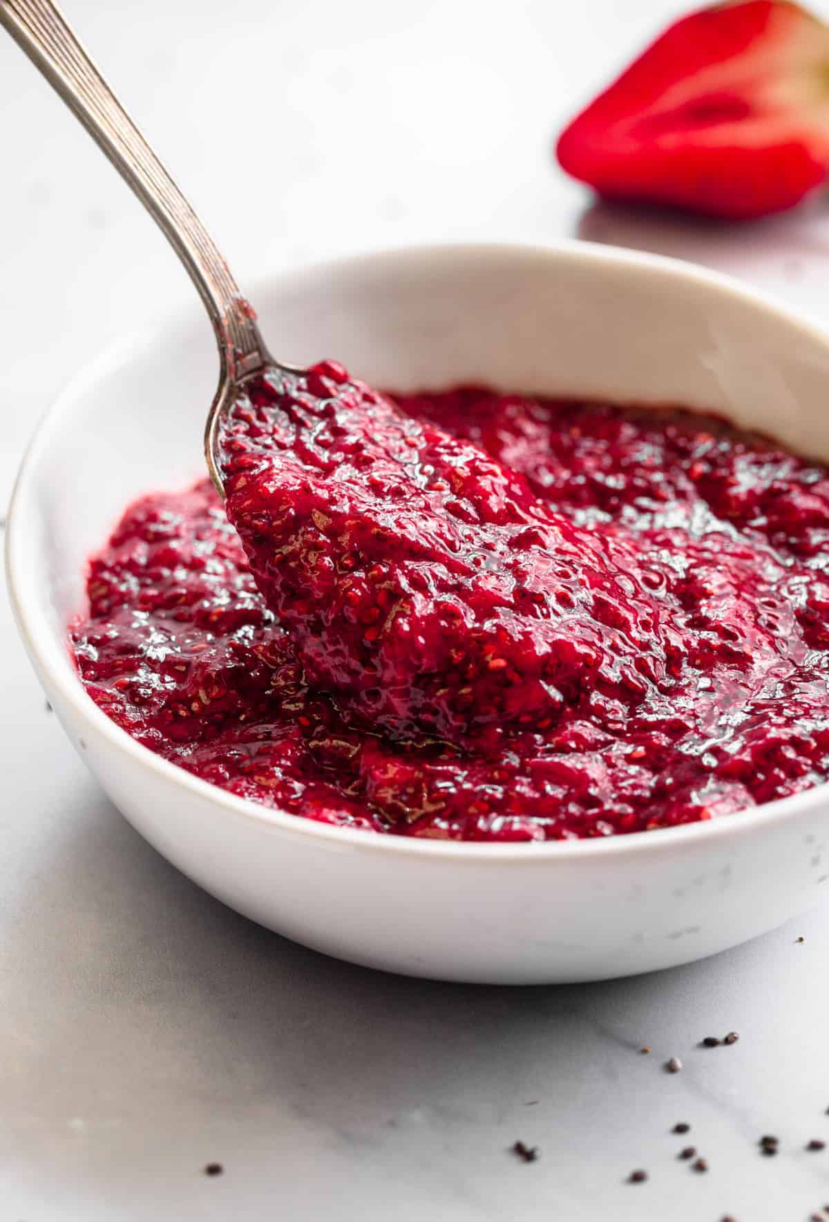 Healthy Strawberry Chia Jam - This easy Strawberry Chia Jam is refined sugar free, only 4 ingredients and only takes 15 minutes to make! Naturally paleo and vegan too! | #Foodfaithfitness | #glutenfree #healthy #vegan #dairyfree #paleo close up side view of strawberry chia jam in a bowl with spoon