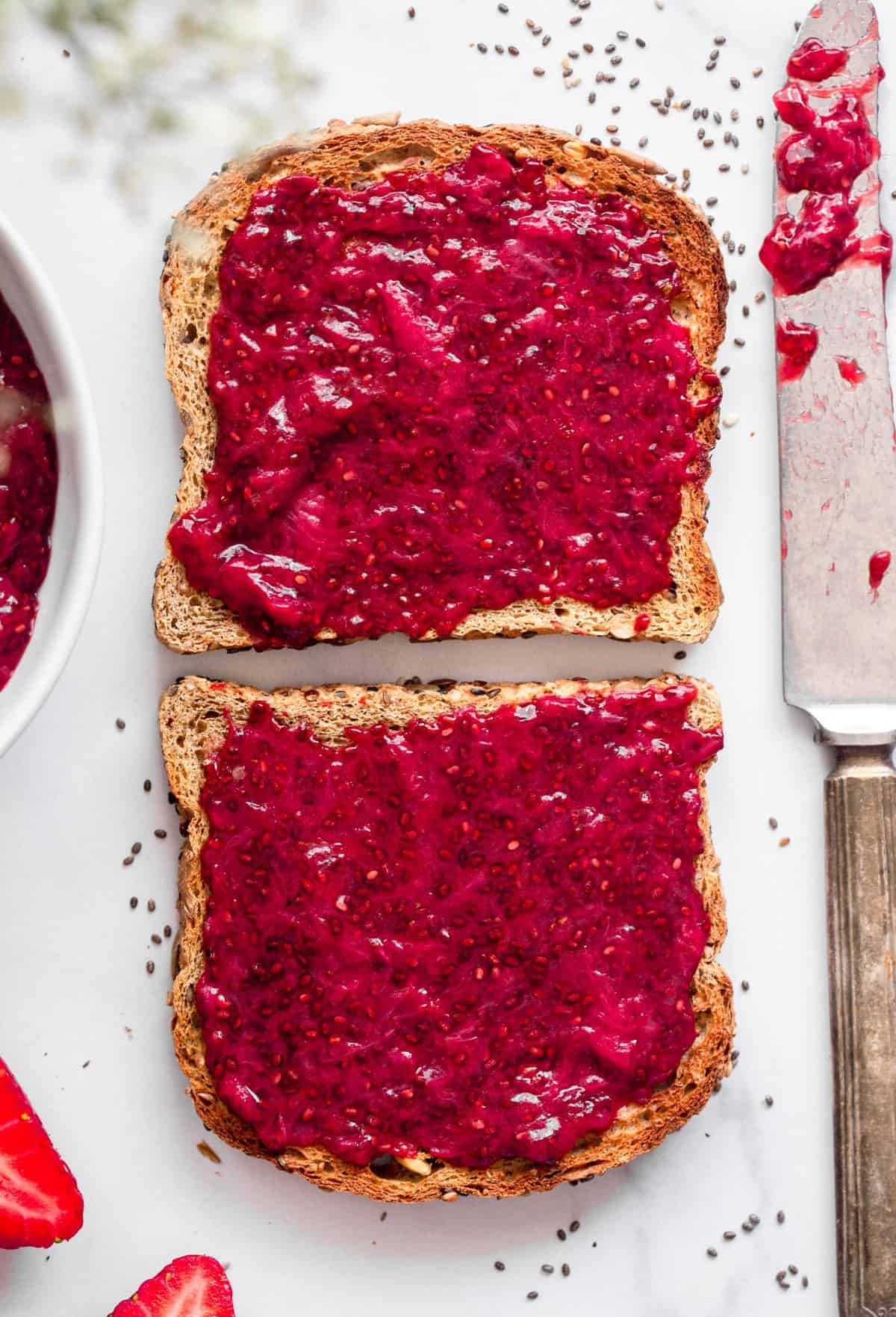 Healthy Strawberry Chia Jam - This easy Strawberry Chia Jam is refined sugar free, only 4 ingredients and only takes 15 minutes to make! Naturally paleo and vegan too! | #Foodfaithfitness | #glutenfree #healthy #vegan #dairyfree #paleo strawberry chia jam spread on 2 slices of toast