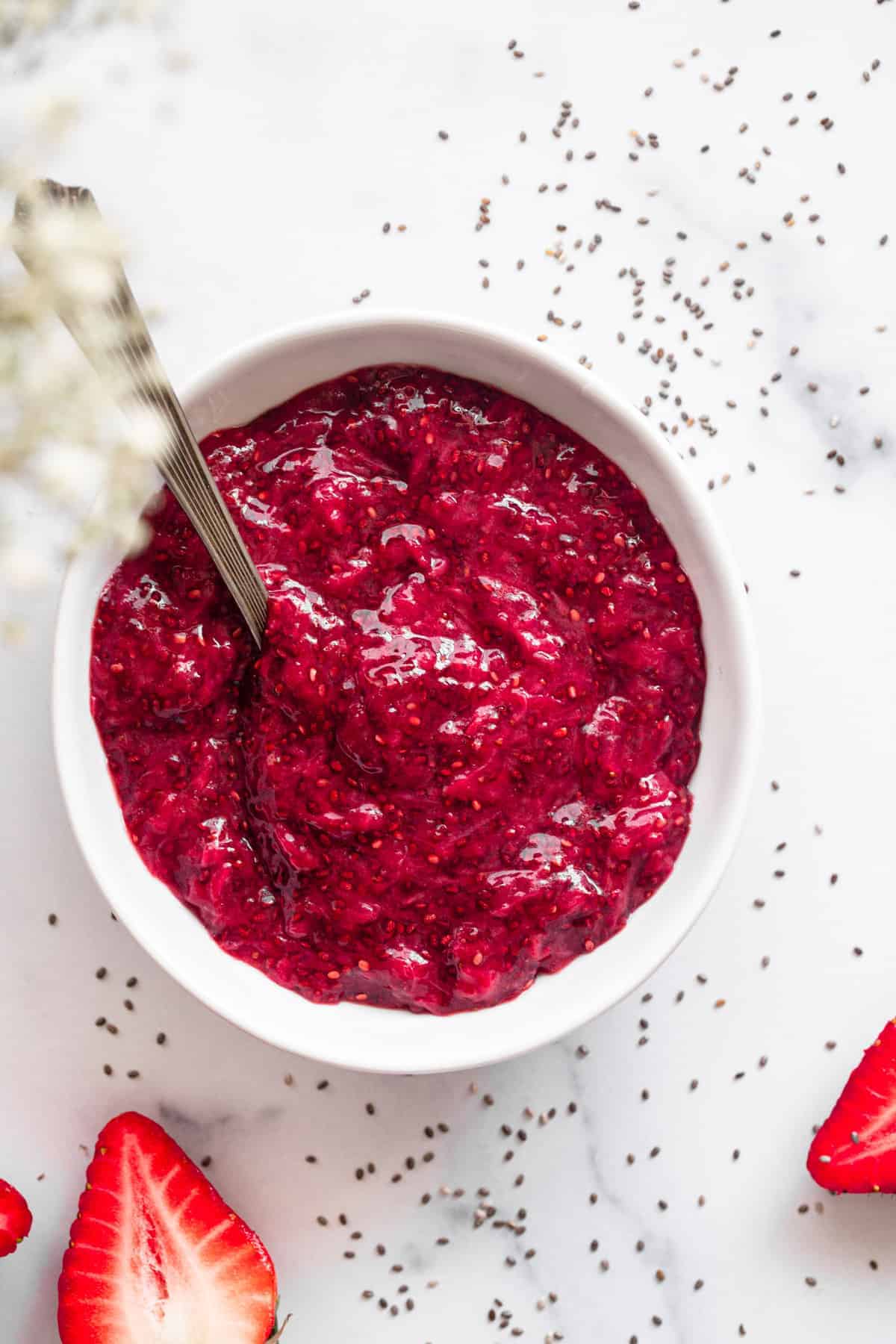 Healthy Strawberry Chia Jam - This easy Strawberry Chia Jam is refined sugar free, only 4 ingredients and only takes 15 minutes to make! Naturally paleo and vegan too! | #Foodfaithfitness | #glutenfree #healthy #vegan #dairyfree #paleo top vie of strawberry chia jam in a bowl with spoon