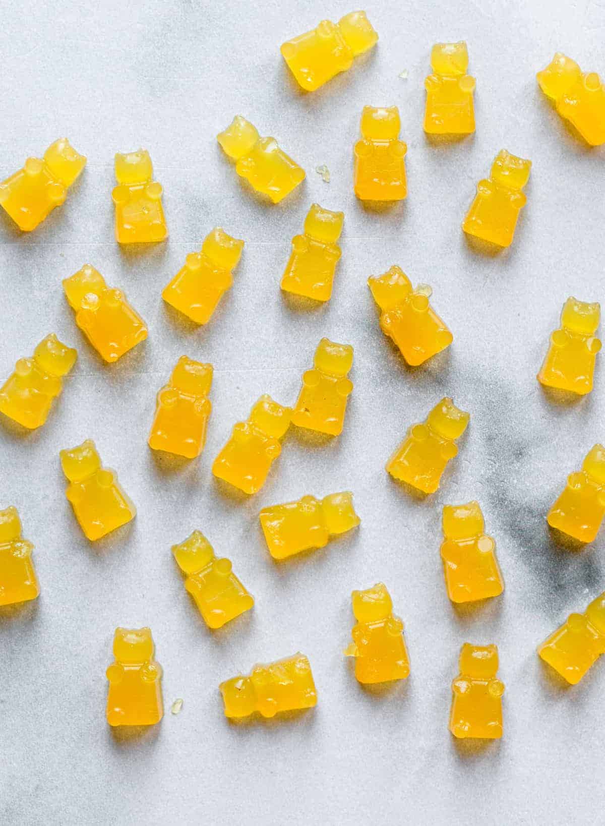 Homemade Healthy Gummies - These Healthy Gummies are only 2 ingredients, have no sugar added and are paleo and whole30 friendly! Kids and adults will love them! | #Foodfaithfitness | #glutenfree #paleo #whole30 #sugarfree scattered healthy gummies on a table