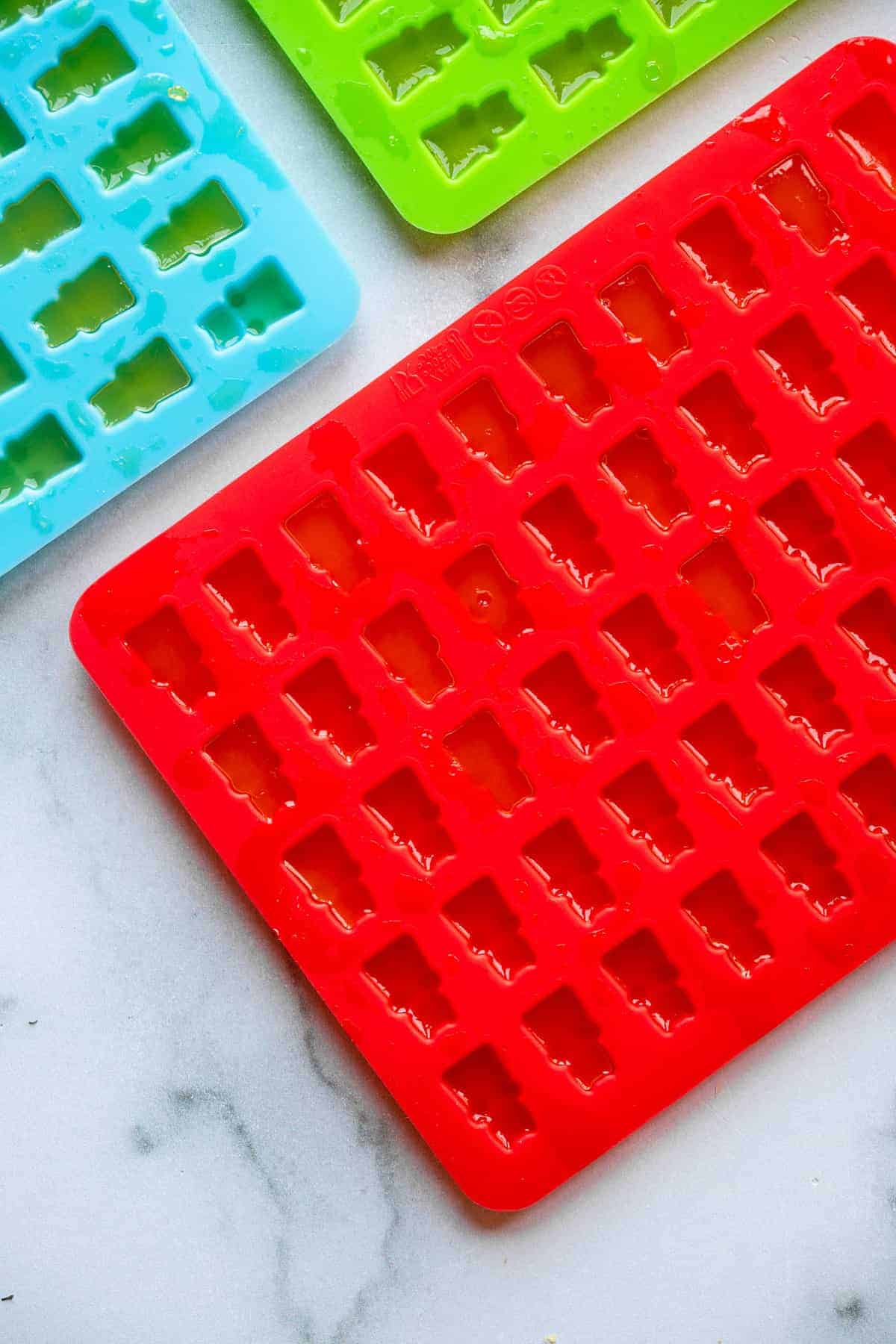 Homemade Healthy Gummies - These Healthy Gummies are only 2 ingredients, have no sugar added and are paleo and whole30 friendly! Kids and adults will love them! | #Foodfaithfitness | #glutenfree #paleo #whole30 #sugarfree gummy bear mold being filled with healthy gummies