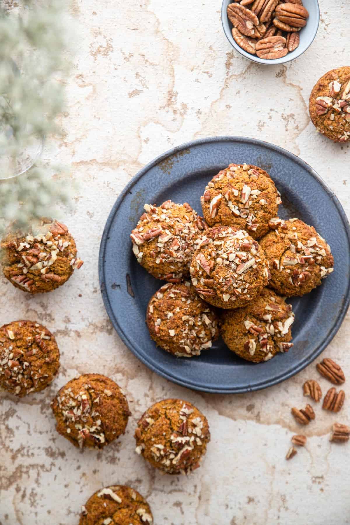 keto pumpkin muffins on a plate with pecans on the side