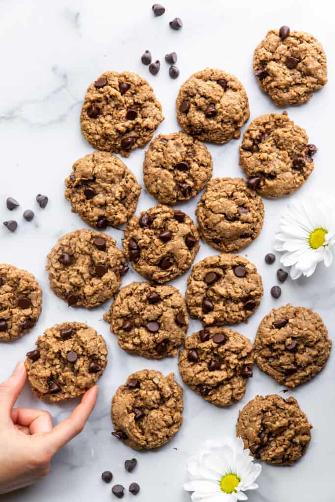 a large batch of Vegan Oatmeal Chocolate Chip Cookies on a table