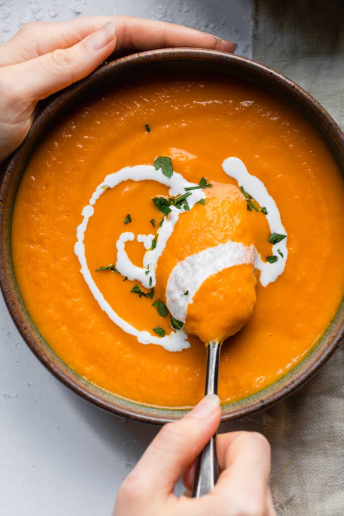 a bowl of Carrot Ginger Soup being stirred