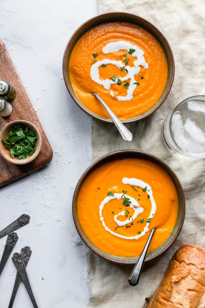 bowls of Carrot Ginger Soup on a table with toppings