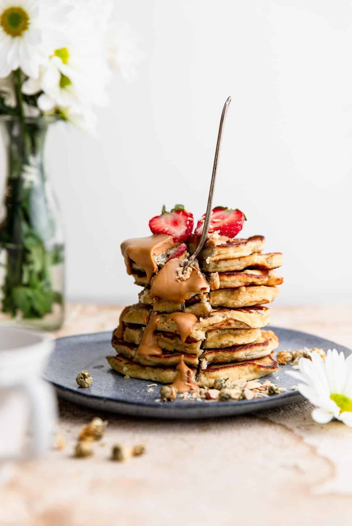 Whole30 Banana Pancakes stacked on a plate with a fork stuck into it